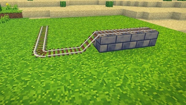A track of rails bending round a corner and climbing a slope onto a stone step.
